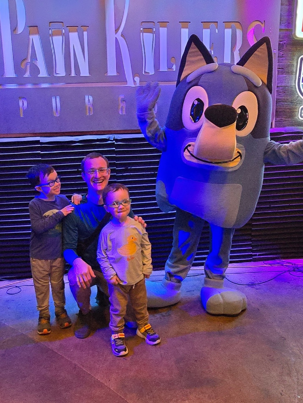 A father and two children meeting Bluey at a dance party