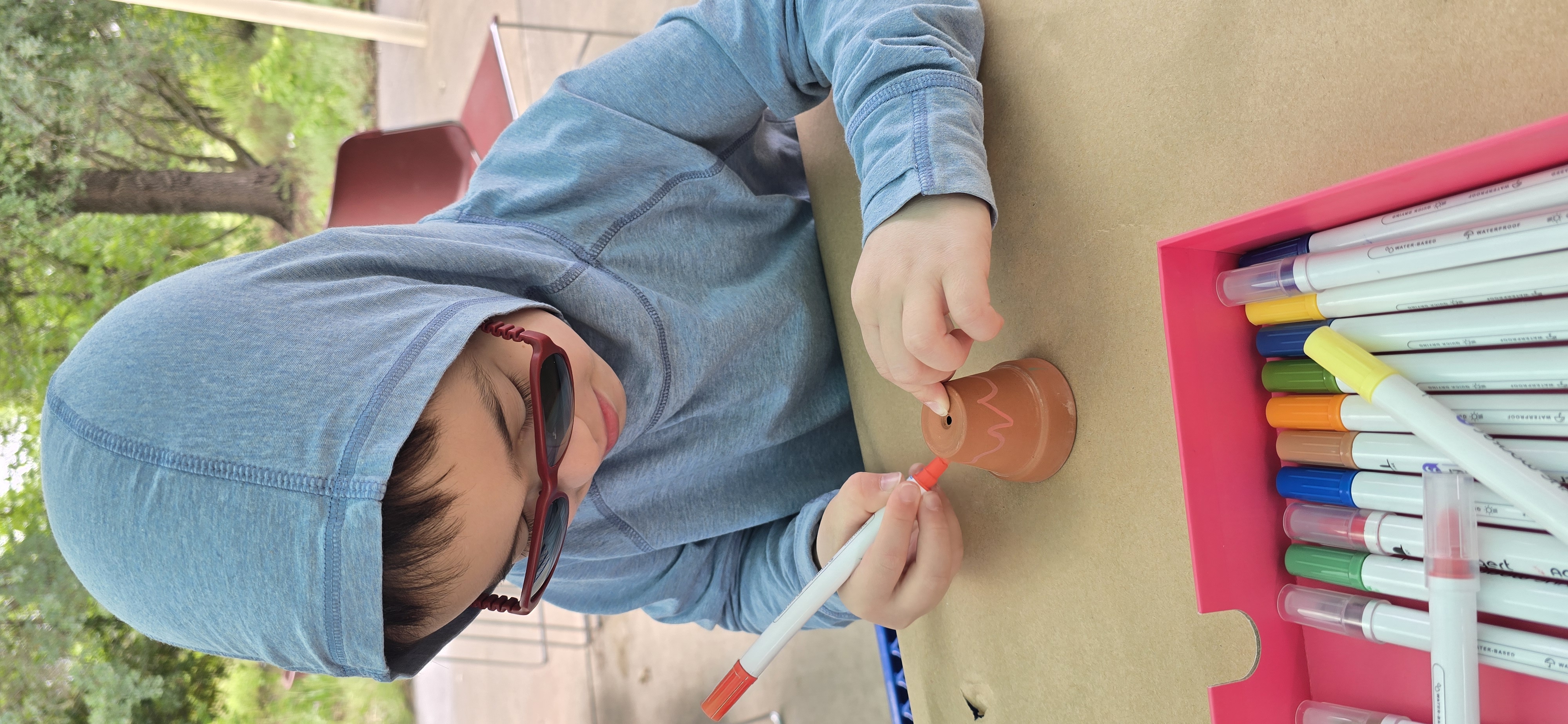 A child painting a clay pot at a Native American cultural exhibit at a local library
